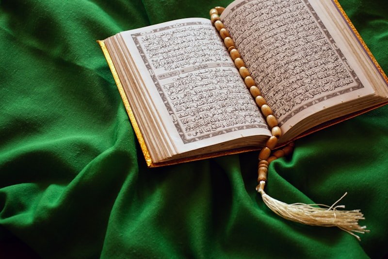 An open Qur'an with prayer beads resting on green velvet